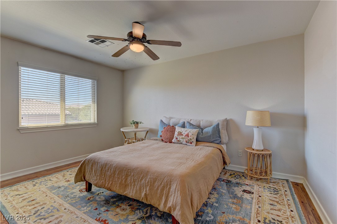 9992 South Sky Parlor Road Las Vegas, NV 89178 - Photo 30 of 42 Bedroom with visible vents, baseboards, a ceiling fan, and wood finished floors