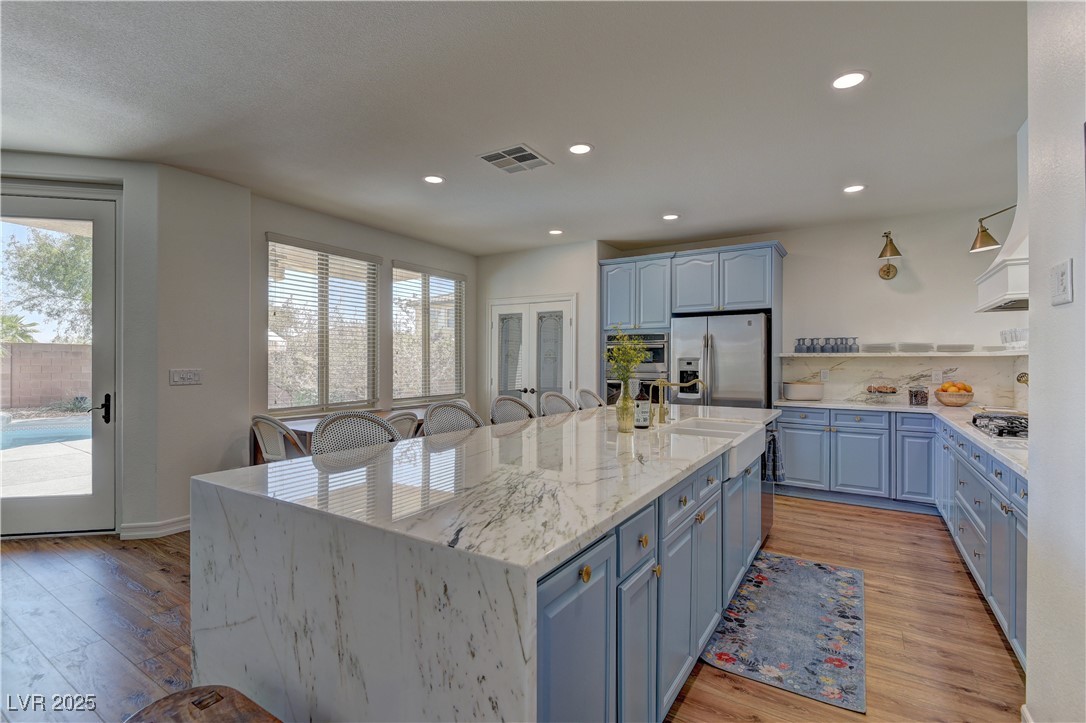 9992 South Sky Parlor Road Las Vegas, NV 89178 - Photo 8 of 42 Kitchen with light wood-style floors, appliances with stainless steel finishes, blue cabinetry, and a wealth of natural light