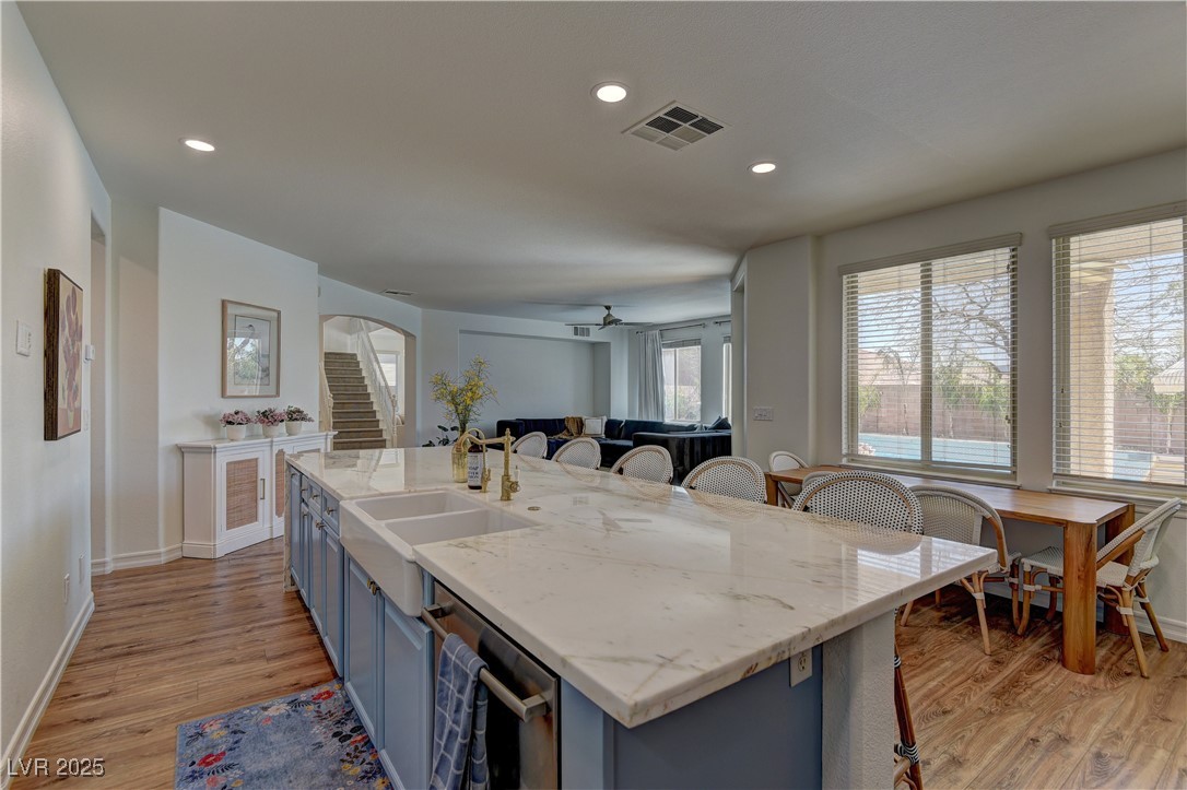 9992 South Sky Parlor Road Las Vegas, NV 89178 - Photo 42 of 42 Kitchen with visible vents, open floor plan, a breakfast bar, light wood-style floors, and blue cabinets