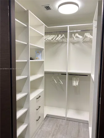 a view of walk in closet with empty racks