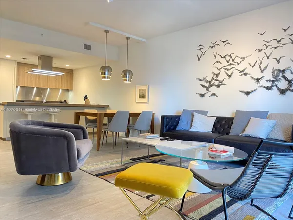 a living room with furniture a rug and kitchen view