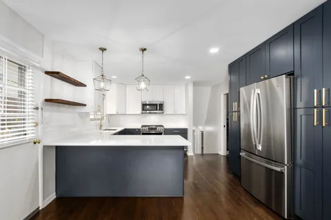 a kitchen with stainless steel appliances a refrigerator a sink a stove a microwave and wooden floor