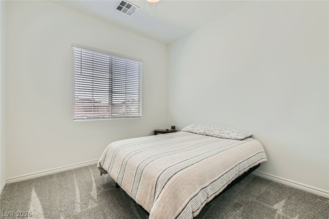 498 Pebble Run Avenue Henderson, NV 89011 - Photo 16 of 47 This naturally lit bedroom features plush carpeting and a large window with privacy blinds.
