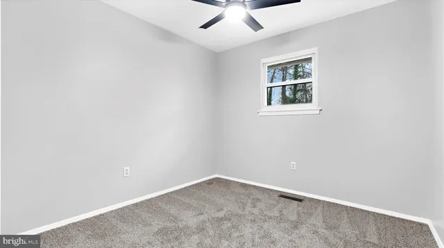 an empty room with a window and ceiling fan
