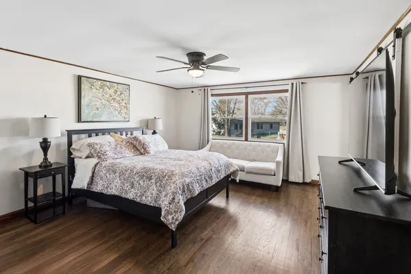 a bedroom with a bed wooden floor and a flat screen tv