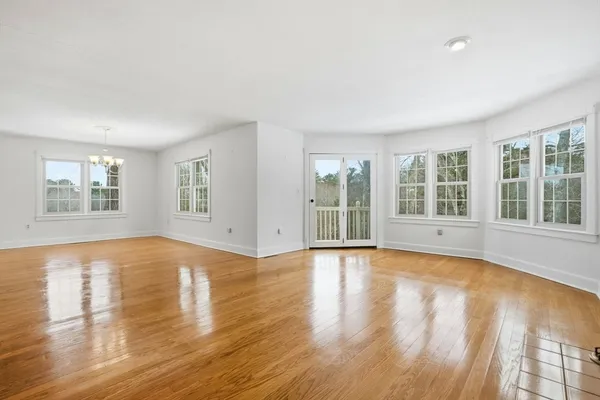 a view of an empty room with wooden floor and windows