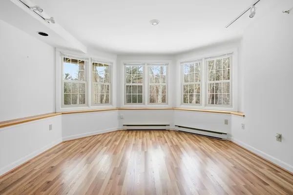an empty room with wooden floor and windows