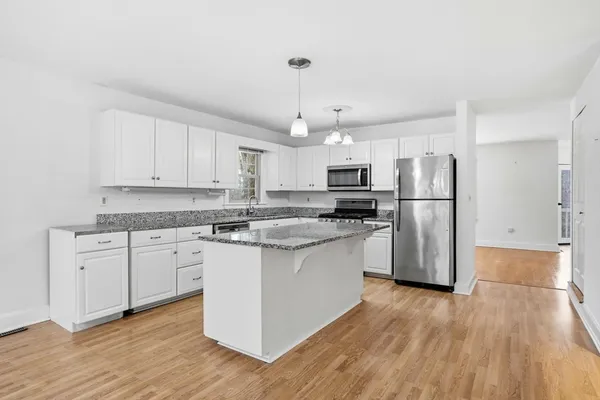 a kitchen with stainless steel appliances granite countertop a refrigerator a sink dishwasher a stove and white countertops with wooden floor