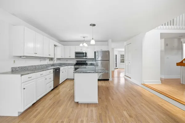 a kitchen with kitchen island granite countertop a sink cabinets and wooden floor