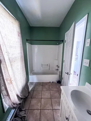 a bathroom with a sink a toilet a window and tub