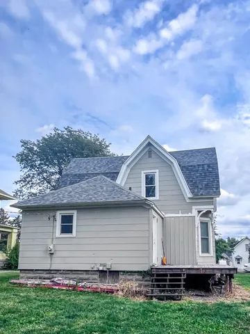 a front view of house with yard and trees in the background