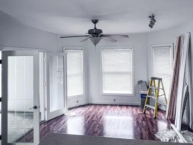 a view of an empty room with a window and wooden floor