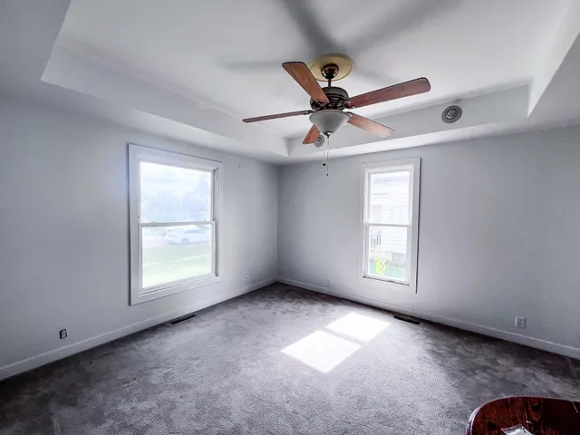 an empty room with a window and a fan