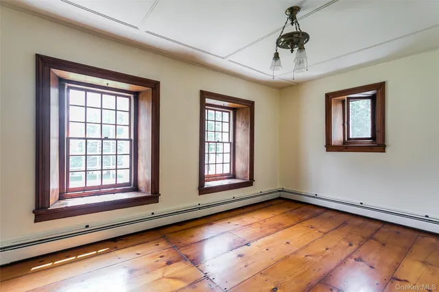 a view of an empty room with window and wooden floor
