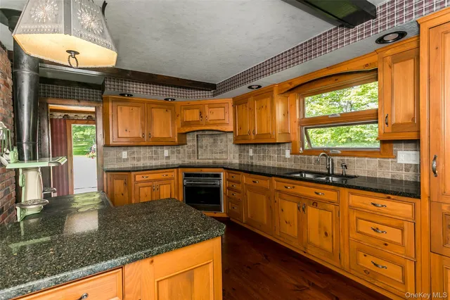 a kitchen with kitchen island granite countertop a sink window and cabinets