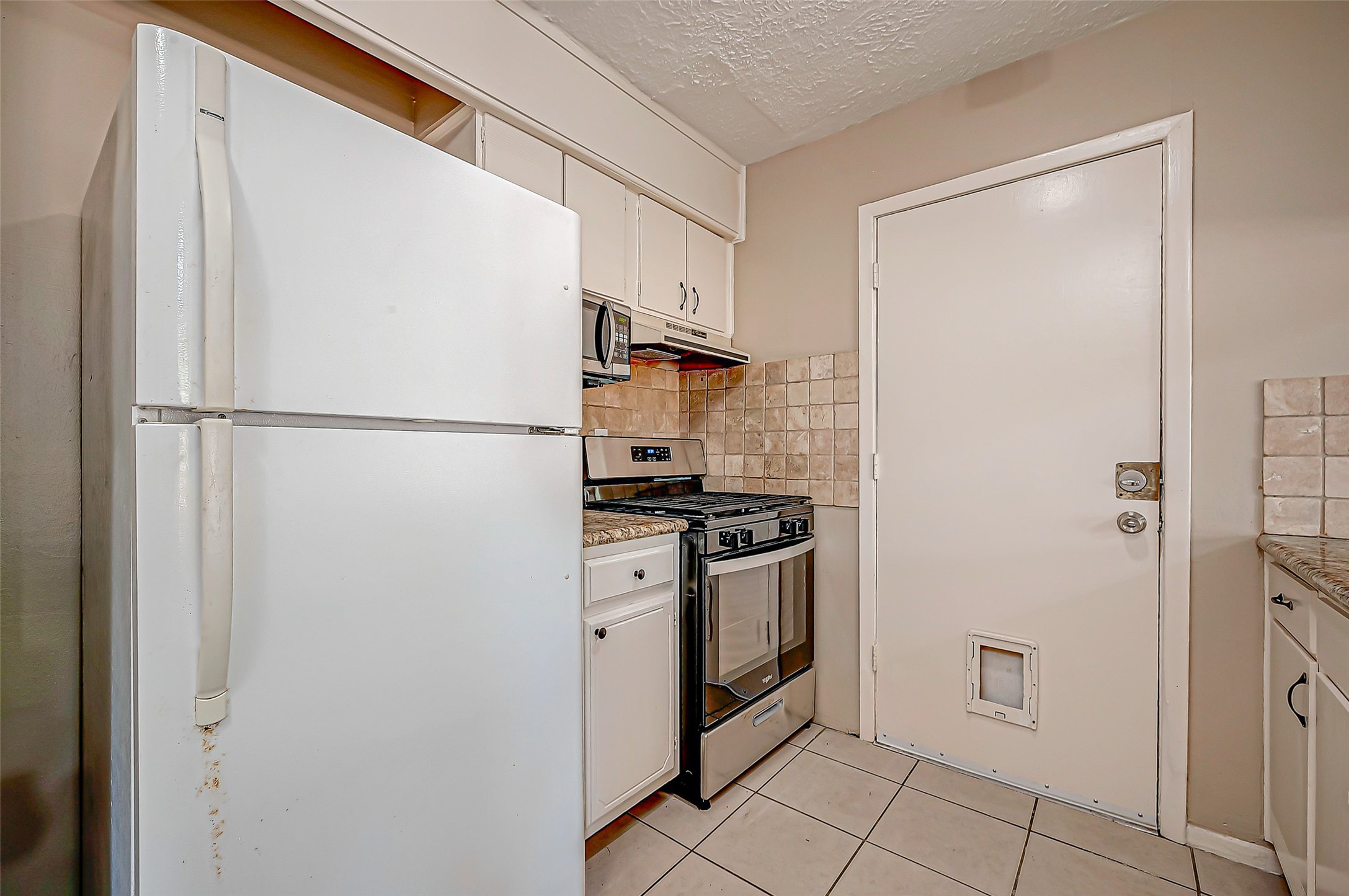 7027 Inkberry Drive Houston, TX 77092 - Photo 14 of 37 a white refrigerator freezer and a stove sitting inside of a kitchen