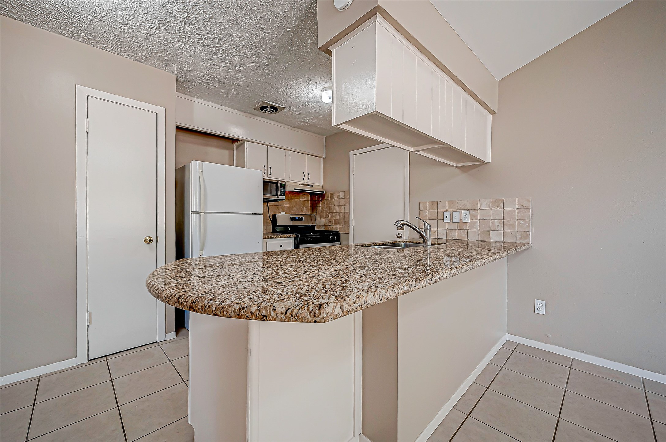 7027 Inkberry Drive Houston, TX 77092 - Photo 17 of 37 a kitchen with stainless steel appliances granite countertop a sink stove and refrigerator