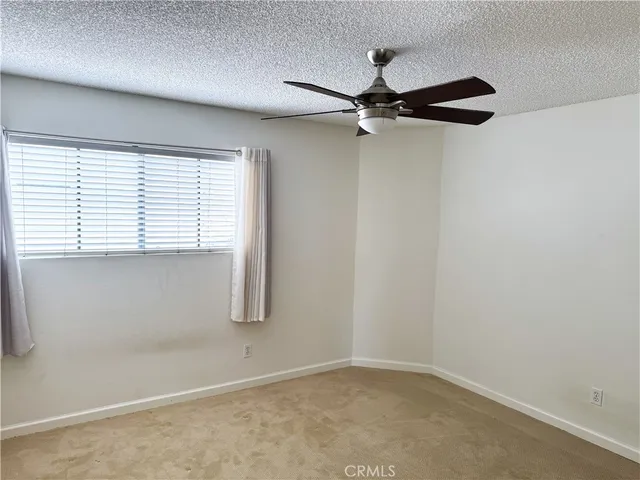 an empty room with a ceiling fan and carpet