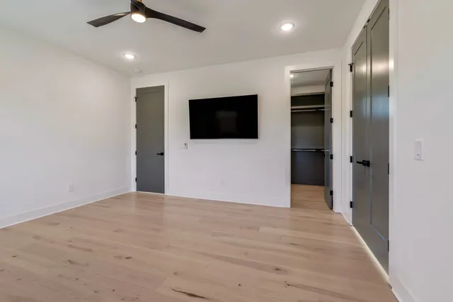 an empty room with wooden floor and a ceiling fan