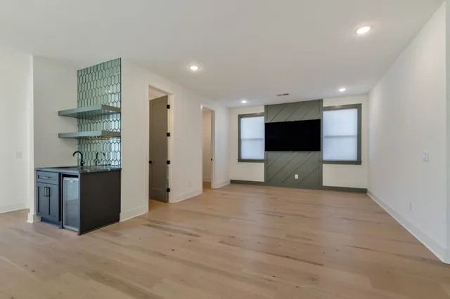 a view of an empty room with kitchen and a window