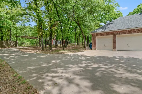 a backyard of a house with large trees and parked