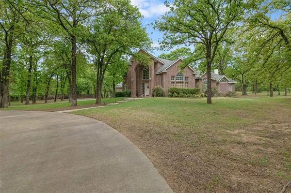 a view of a house with a big yard and large trees