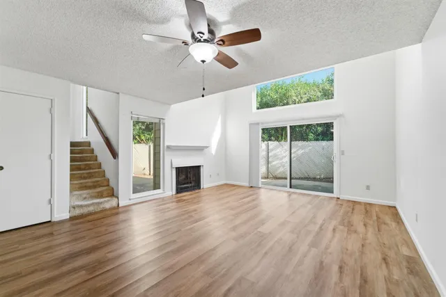 a view of an empty room with wooden floor fireplace and a window