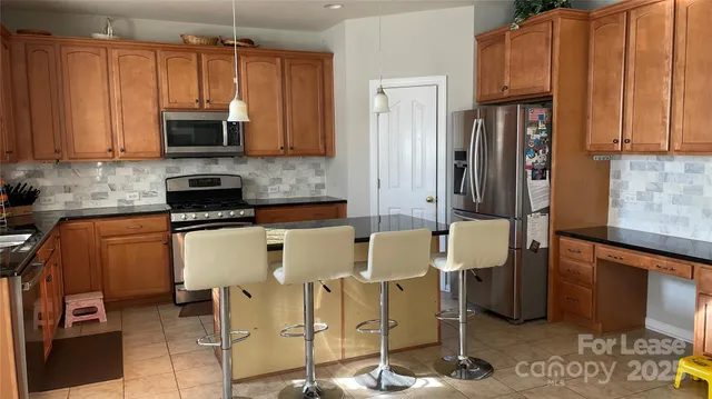 a kitchen with stainless steel appliances a stove a sink cabinets and a window