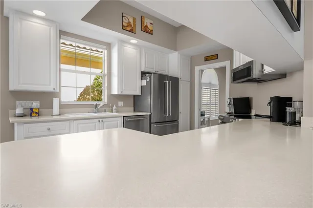 a large kitchen with stainless steel appliances a large counter top a stove a refrigerator and a sink