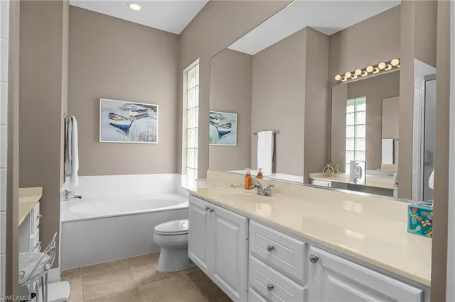 a bathroom with a granite countertop sink a toilet a large mirror and shower