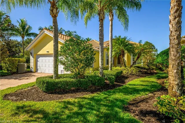 a view of a house with a yard and palm trees