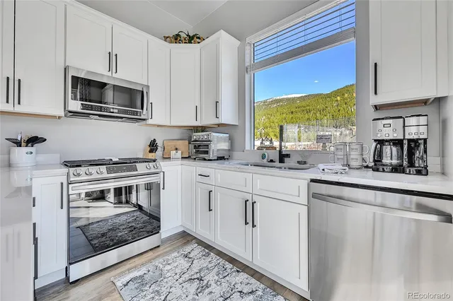 a kitchen with stainless steel appliances granite countertop a stove a sink and a microwave