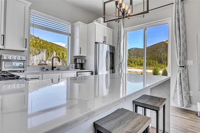 a kitchen with stainless steel appliances granite countertop a refrigerator a stove and white cabinets with wooden floors