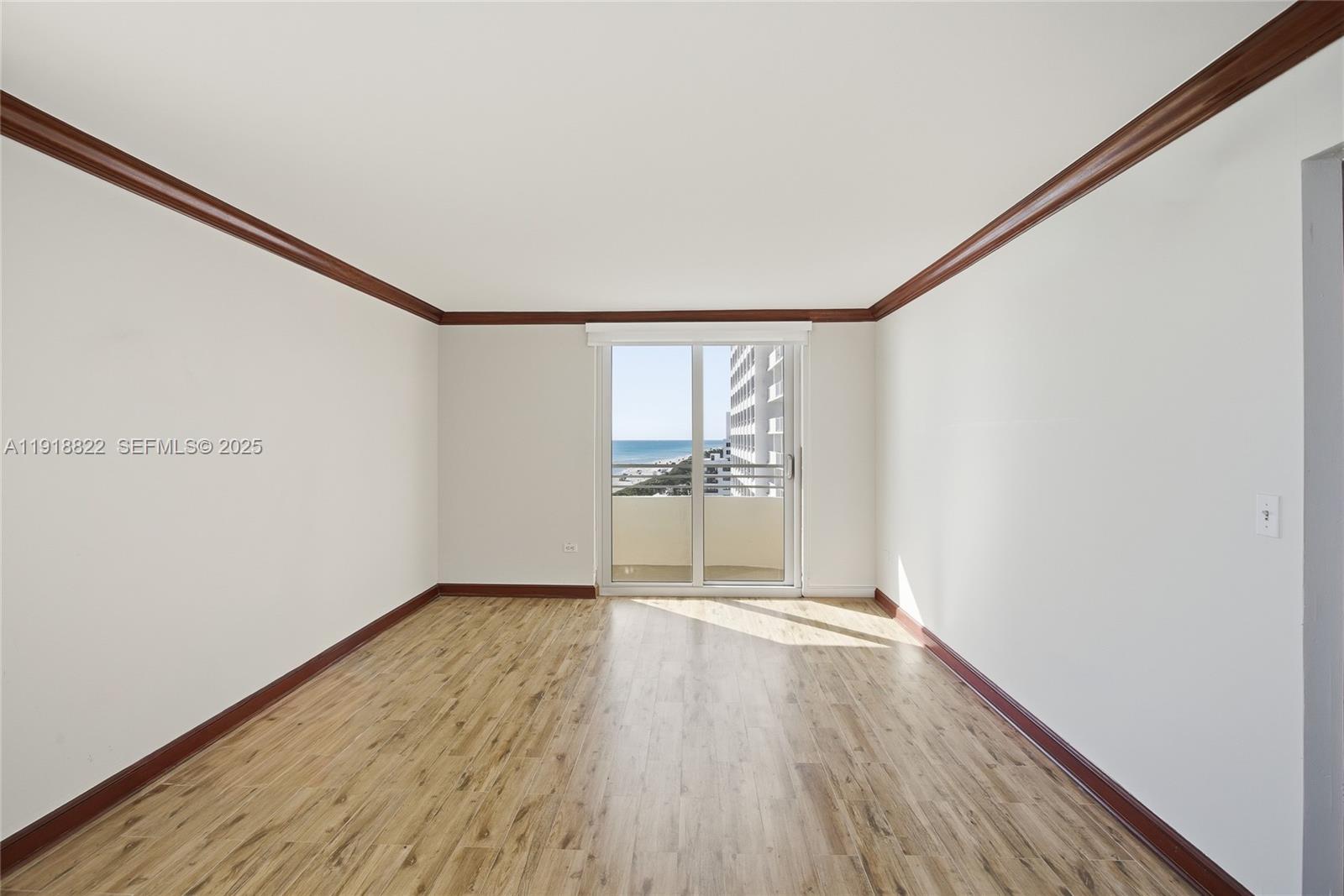 5555 Collins Avenue, Unit 12N Miami Beach, FL 33140 - Photo 30 of 49 a view of an empty room with wooden floor and a window