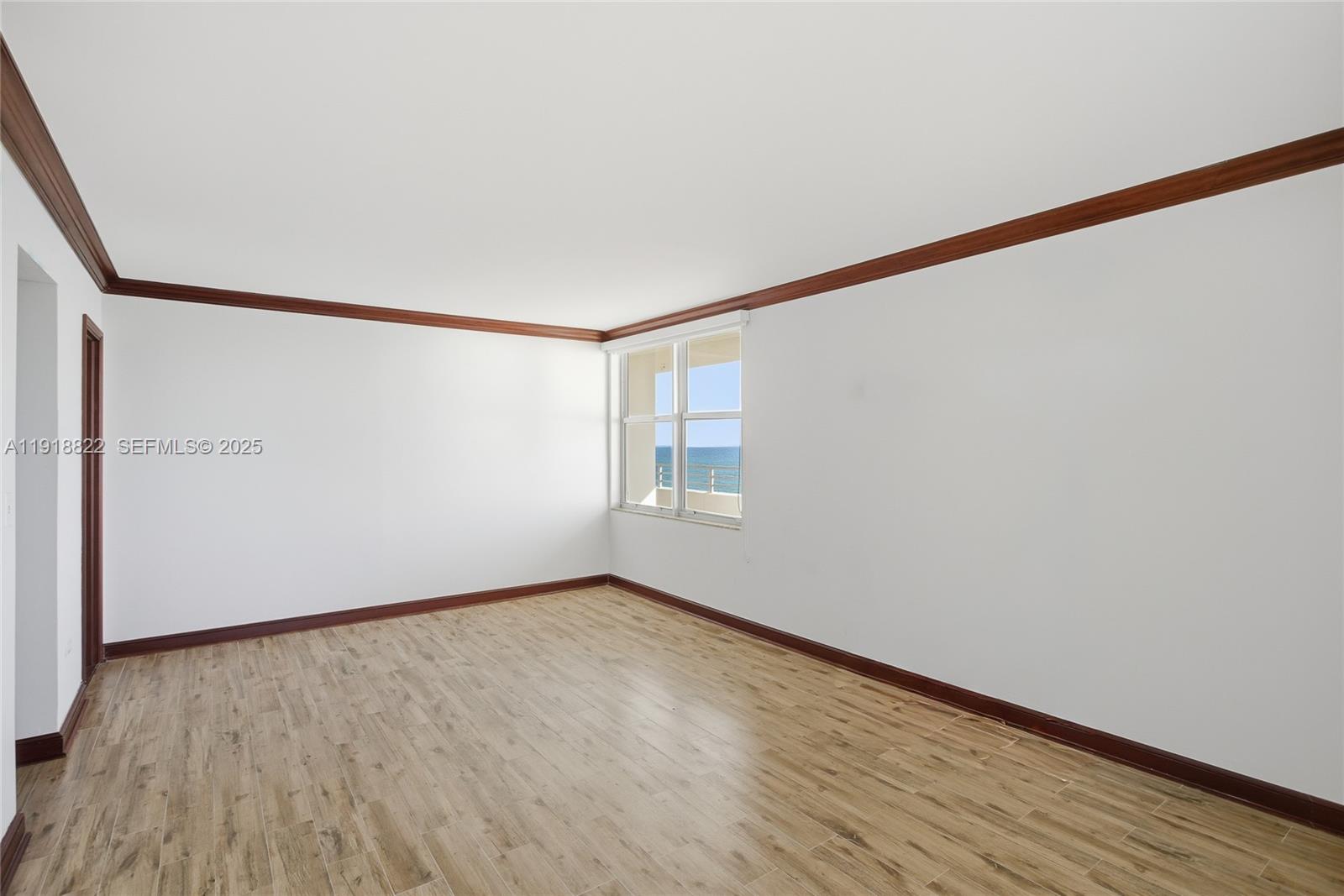 5555 Collins Avenue, Unit 12N Miami Beach, FL 33140 - Photo 31 of 49 a view of an empty room with wooden floor and a window