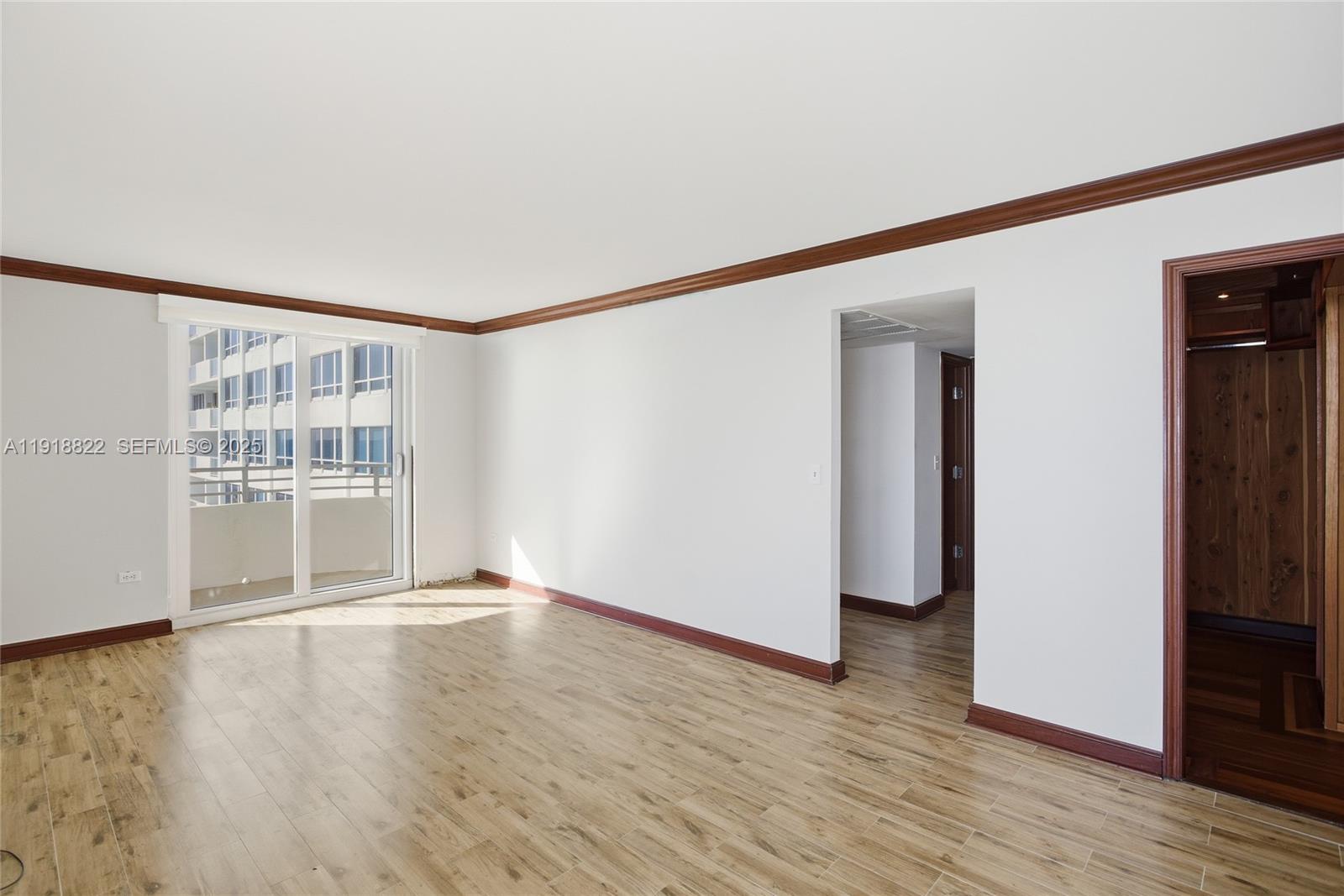 5555 Collins Avenue, Unit 12N Miami Beach, FL 33140 - Photo 32 of 49 a view of an empty room with wooden floor and a window