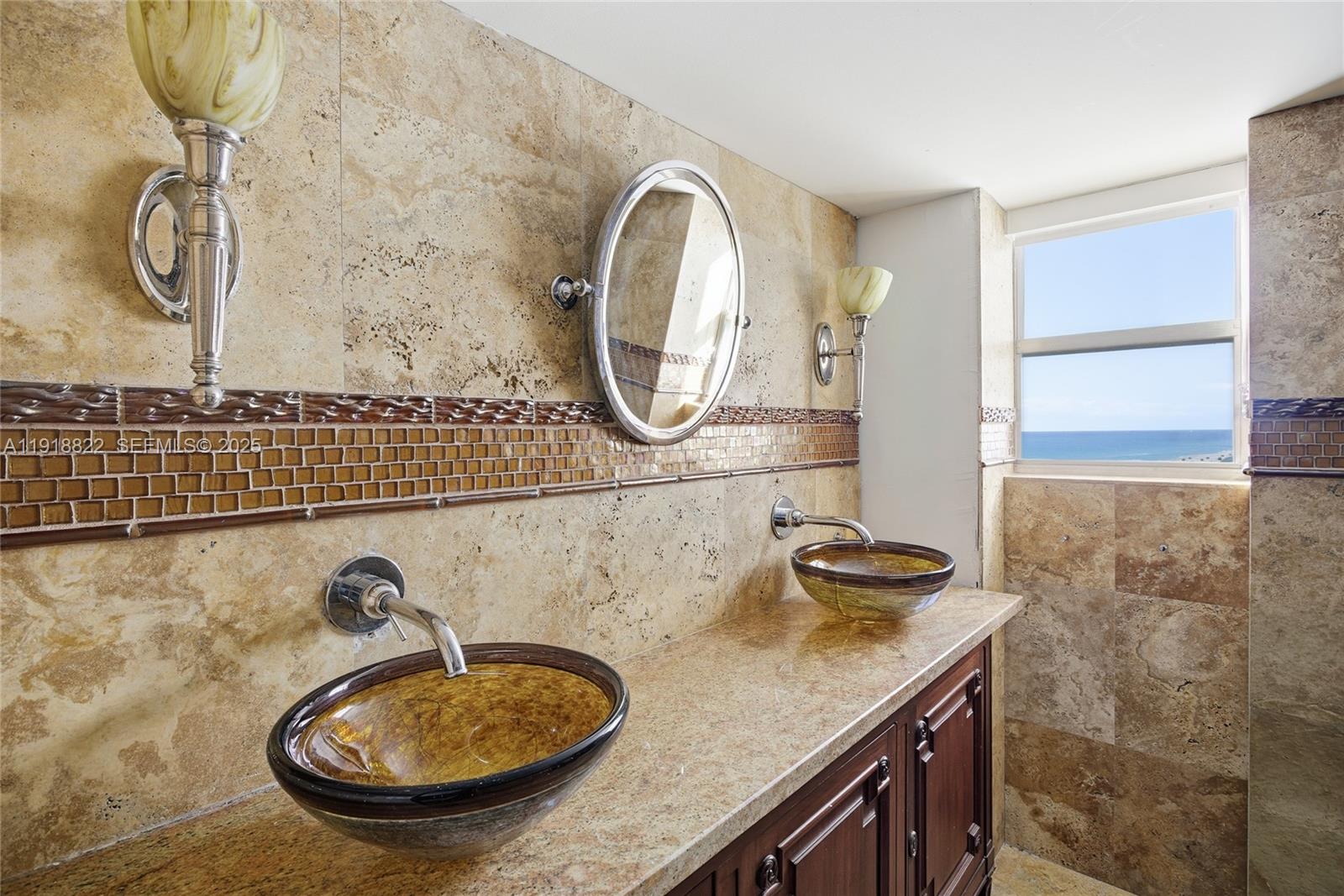 5555 Collins Avenue, Unit 12N Miami Beach, FL 33140 - Photo 34 of 49 a bathroom with a granite countertop double vanity sink and mirror