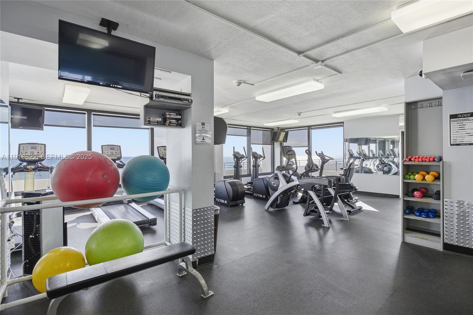 5555 Collins Avenue, Unit 12N Miami Beach, FL 33140 - Photo 36 of 49 a room with gym equipment and a flat screen tv