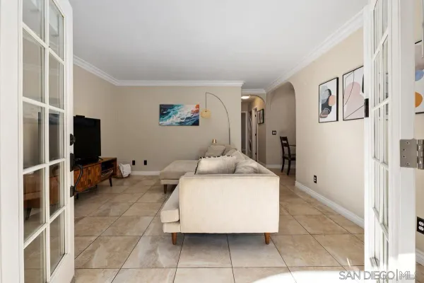 a living room with furniture a flat screen tv and a refrigerator