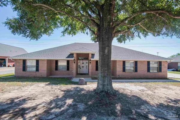 a front view of a house with a yard tree and wooden fence