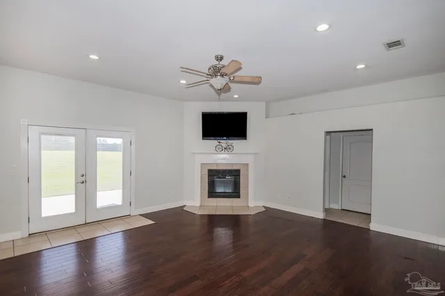 an empty room with wooden floor fan and windows