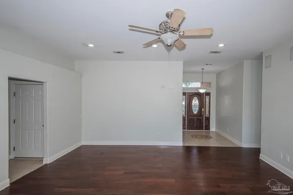 a view of an empty room with a window and wooden floor