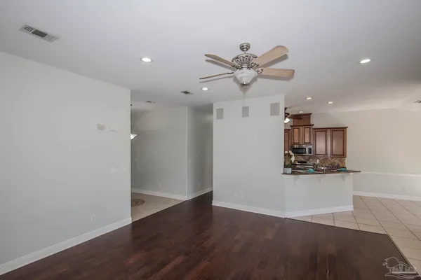 an empty room with wooden floor a ceiling fan a fireplace and windows