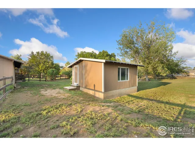 a view of a patio with table and chairs and floor to ceiling window with yard