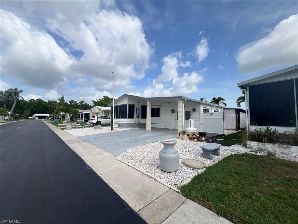 128 Mediterranean Way, Unit 128 Naples, FL 34104 - Photo 3 of 41 featuring driveway, a carport, and a sunroom
