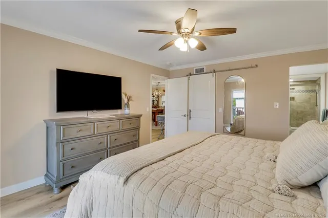 a bedroom with a large bed a flat tv screen and a chandelier