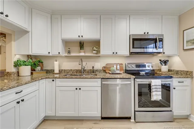 a kitchen with granite countertop white cabinets and stainless steel appliances
