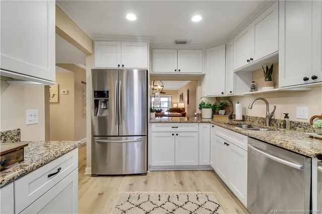 a kitchen with granite countertop a refrigerator sink and cabinets