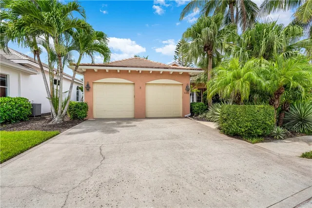 a view of a white house with a yard and palm trees