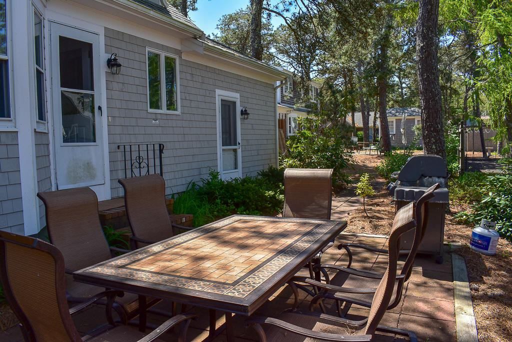 61 Bain Road Dennis Port, MA 02639 - Photo 20 of 22 a view of a patio with table and chairs and potted plants with wooden floor and fence